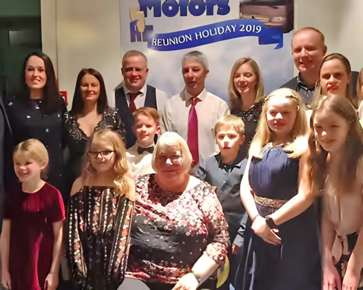 A group photo in front of a Reunion Holiday 2019 banner
